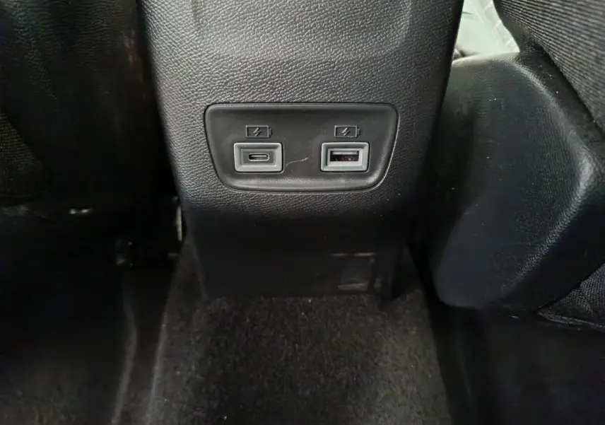 Prise USB-C et USB-A pour recharge à l'arrière d'une Peugeot 208 gris clair, vue centrée en intérieur.