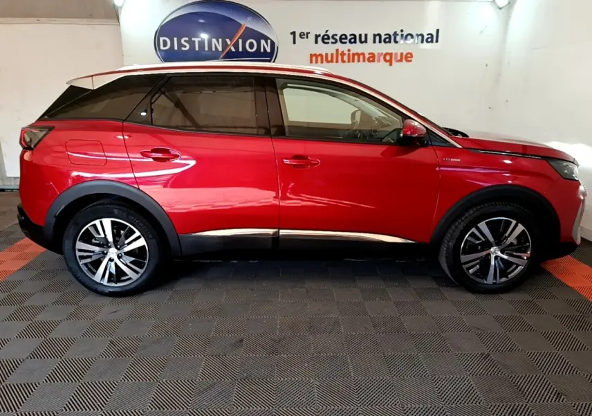 Profil droit d’un Peugeot 3008 hybride rechargeable rouge, avec jantes alliage et toit noir en intérieur showroom.