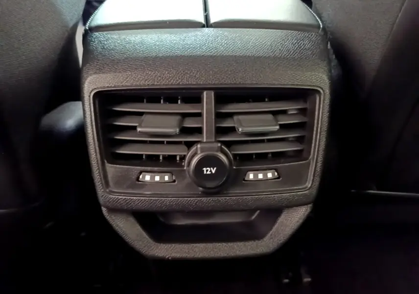 Gros plan sur la sortie d’air arrière noire avec prise 12V et commandes de chauffage du Peugeot 3008 hybride rechargeable.