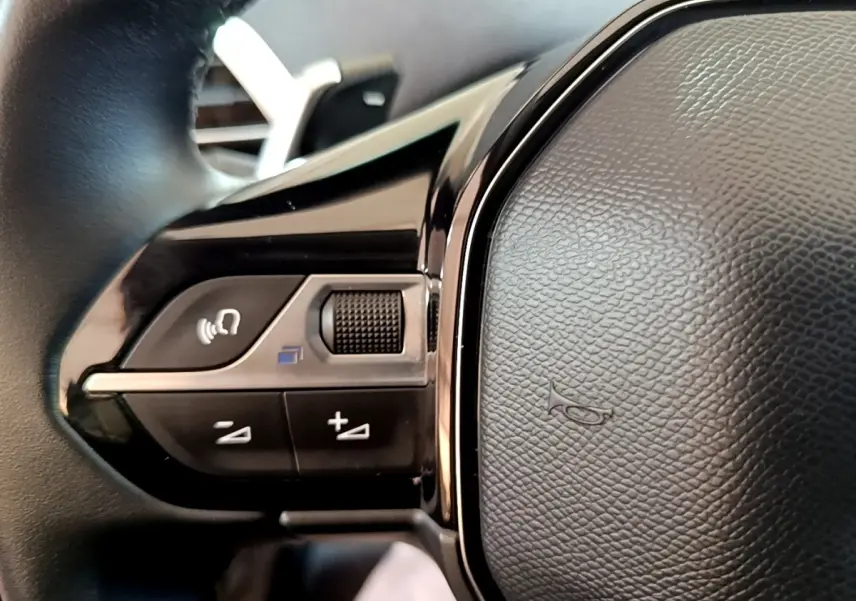 Gros plan sur les commandes gauche du volant cuir noir du Peugeot 3008 hybride rechargeable 2021.