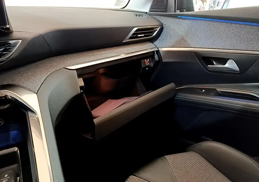 Vue intérieure côté passager du Peugeot 3008 hybride 2021 avec boîte à gants ouverte et éclairage d’ambiance bleu.