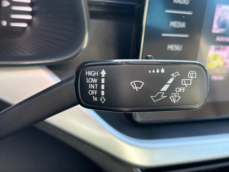 Gros plan sur la commande des essuie-glaces du Skoda Kamiq 2023, intérieur noir avec écran tactile en arrière-plan.