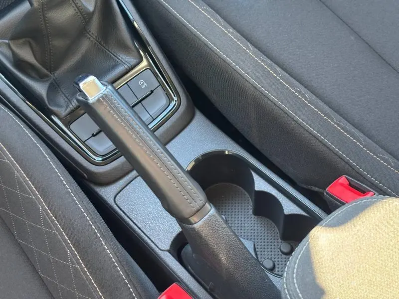 Gros plan sur le frein à main en cuir et le tissu noir quadrillé gris des sièges de la Skoda Kamiq 2023 Ambition.