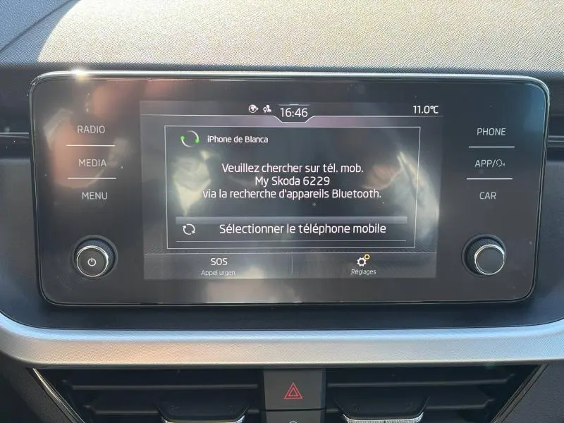 Écran tactile central du Skoda Kamiq 2023 affichant la connexion Bluetooth avec un iPhone, entouré de commandes multimédia.