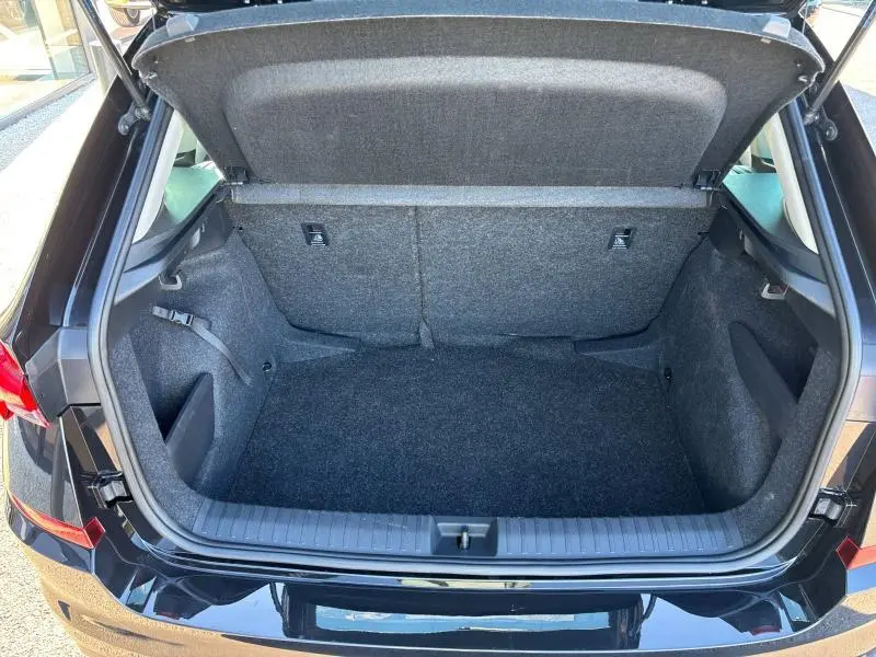 Coffre ouvert vu de l'arrière d'un Skoda Kamiq 1.5 TSI noir nacré, espace de chargement vide et doublure grise.