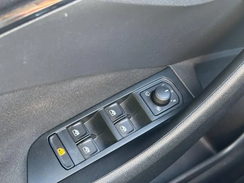 Gros plan sur les commandes des vitres électriques et réglage des rétroviseurs côté conducteur d'une Skoda Kamiq noir Magic nacré.