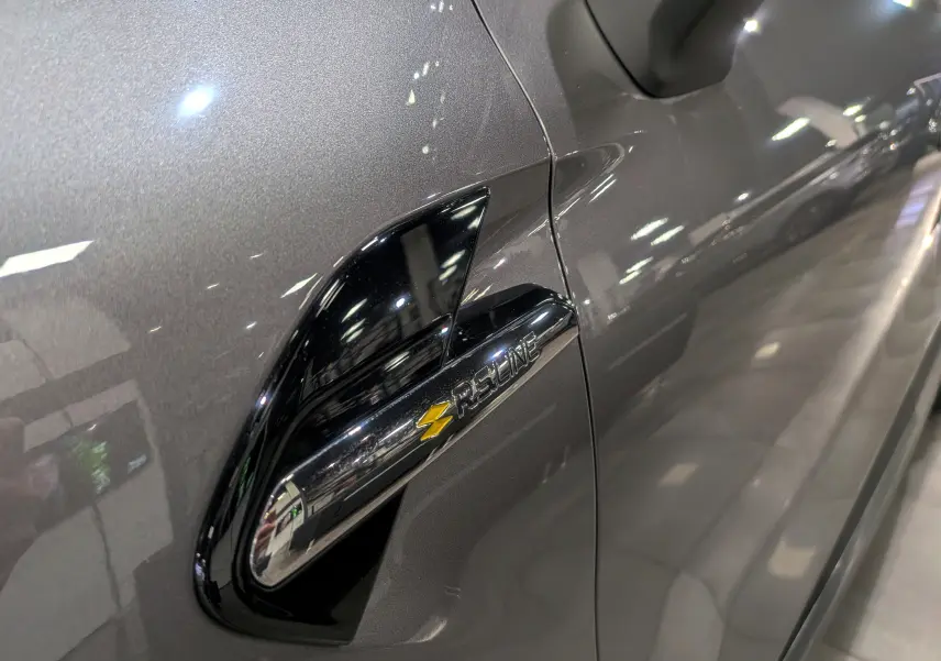 Gros plan sur l'aile avant gauche gris Cassiopé du Renault Captur R.S. Line avec logo distinctif jaune et noir.