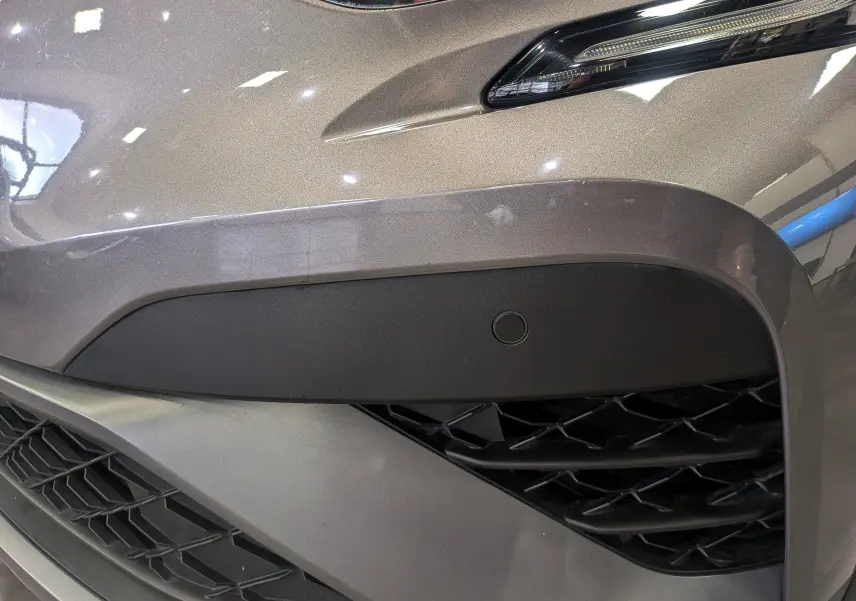 Gros plan sur l'avant droit gris Cassiopé du Renault Captur 2022, mettant en valeur la calandre et le capteur de stationnement.