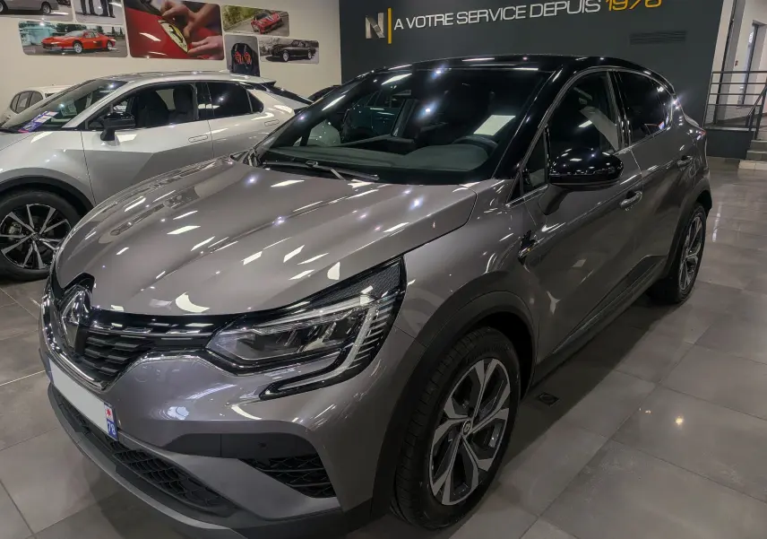 Vue 3/4 avant droit d'un Renault Captur TCe 160 R.S. Line gris Cassiopé avec toit noir en showroom.