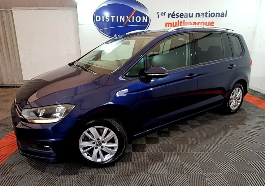 Volkswagen Touran bleu 3/4 avant droit, avec jantes alliage et rétroviseurs noirs brillants en intérieur showroom