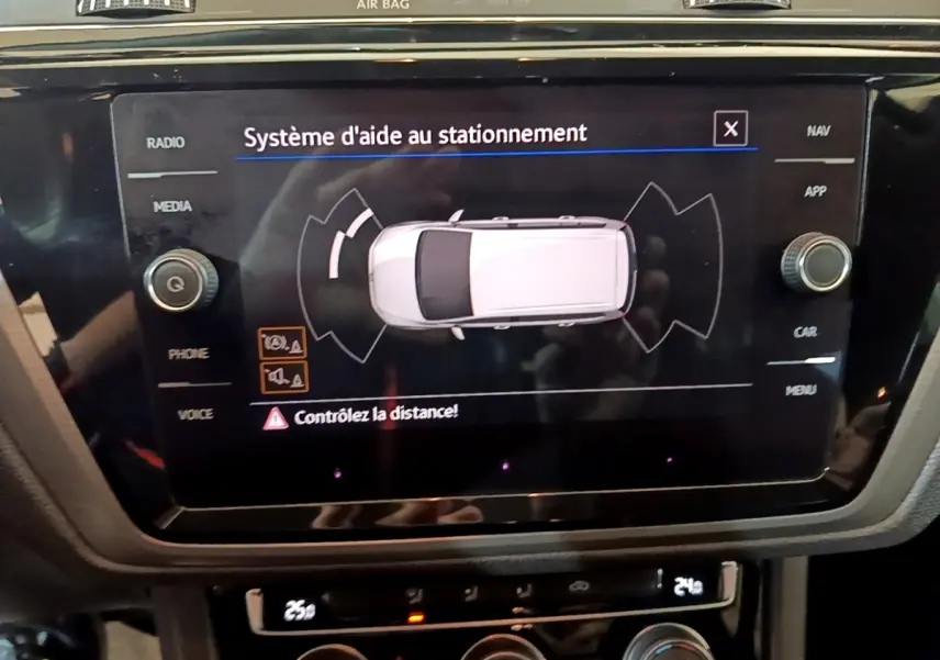Écran tactile central affichant le système d'aide au stationnement du Volkswagen Touran 1.5 TSI bleu, vue intérieure console centrale.