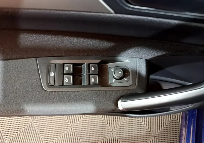 Vue rapprochée des commandes de lève-vitres et rétroviseurs côté conducteur du Volkswagen Touran bleu 2021.