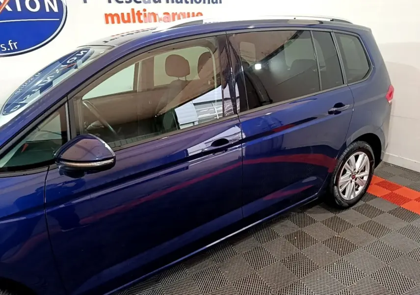 Vue latérale côté gauche d'un Volkswagen Touran bleu 2021 avec vitres teintées et jantes alliage.