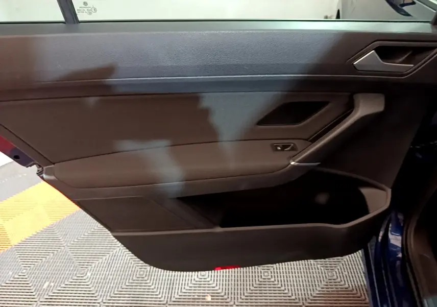 Porte intérieure côté gauche noire du Volkswagen Touran 1.5 TSI EVO DSG7 United bleu, avec poignée et commande de vitre.