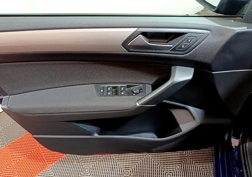 Intérieur côté gauche de la porte d'une Volkswagen Touran bleu 2021, avec commandes de vitres et poignée argentée.