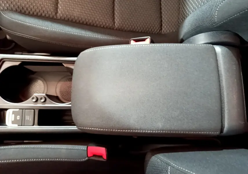 Vue plongeante sur l'accoudoir central noir et les sièges tissu gris du Volkswagen Touran 2021.