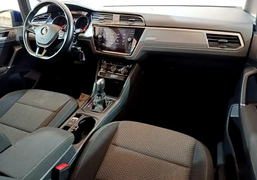 Intérieur avant du Volkswagen Touran 2021, vue côté conducteur, tableau de bord noir avec écran tactile central.