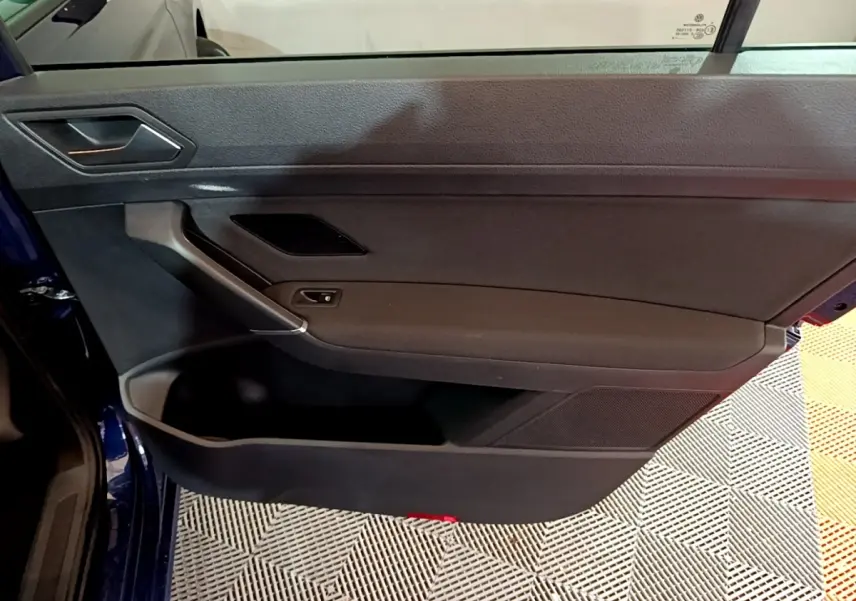 Porte intérieure côté gauche noire du Volkswagen Touran bleu 3/4 avant, avec poignée et haut-parleur intégrés.