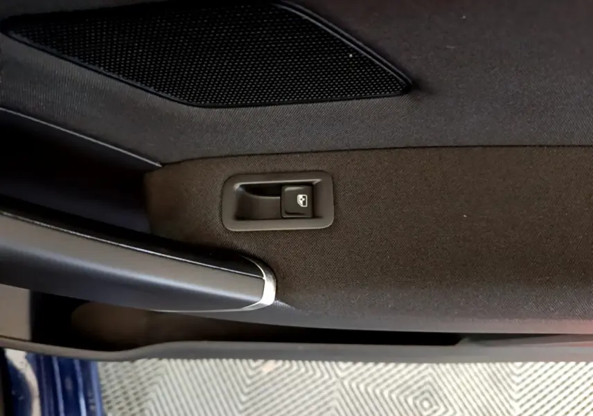 Gros plan sur la poignée intérieure et le bouton de verrouillage de la porte côté gauche d’un Volkswagen Touran bleu.