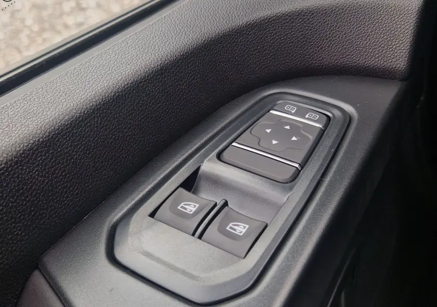 Gros plan sur les commandes électriques des vitres et des rétroviseurs côté conducteur du Renault Trafic Fourgon gris Highland.