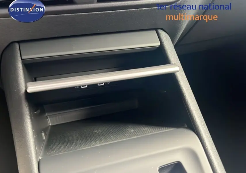 Gros plan sur la console centrale noire du Volkswagen Tiguan 2026, mettant en valeur un espace de rangement avec ports USB visibles.
