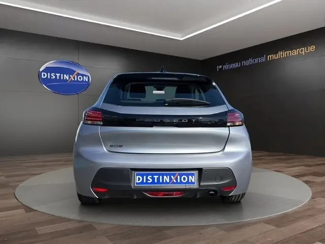 Vue arrière d'une Peugeot 208 gris clair 2025, avec feux LED et logo distinctif sur fond noir brillant.