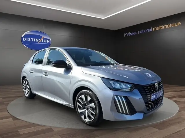Peugeot 208 100 ch Style gris clair vue 3/4 avant droit, avec calandre noire distinctive et jantes alliage modernes.