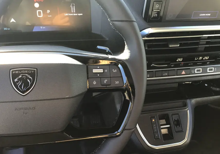Vue rapprochée du volant et tableau de bord noir du Peugeot Expert Fourgon blanc 2024 avec commandes intégrées et écran digital.