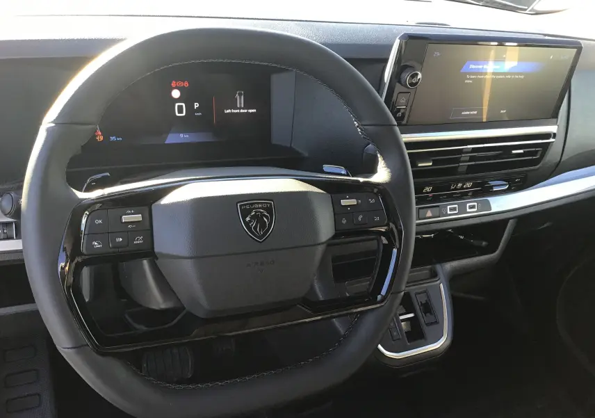 Vue rapprochée du volant noir et du tableau de bord numérique du Peugeot Expert Fourgon 2024, avec écran tactile et commandes intégrées.