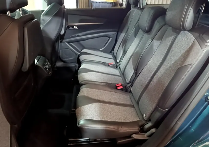 Vue latérale droite sur la banquette arrière grise et noire du Peugeot 5008 bleu, avec ceinture rouge visible.