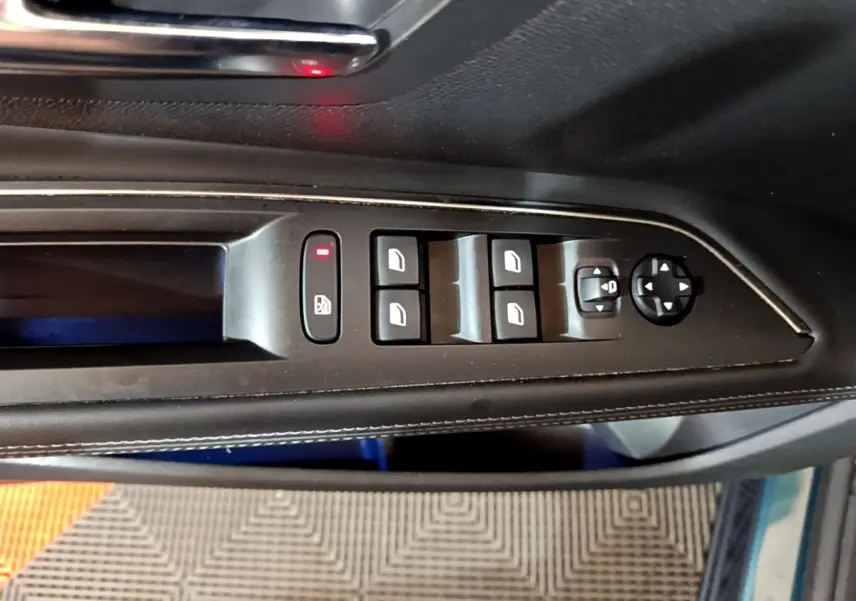 Vue rapprochée des commandes de lève-vitres et réglage des rétroviseurs côté conducteur du Peugeot 5008 bleu.