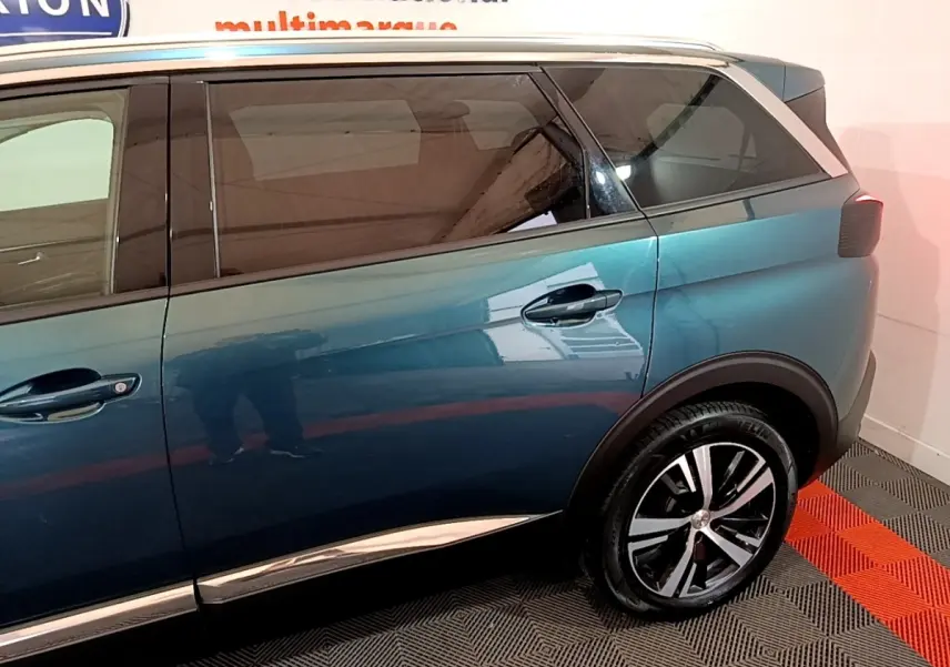Vue latérale droite du Peugeot 5008 bleu 2018 avec jantes alliage et vitres teintées dans un showroom.