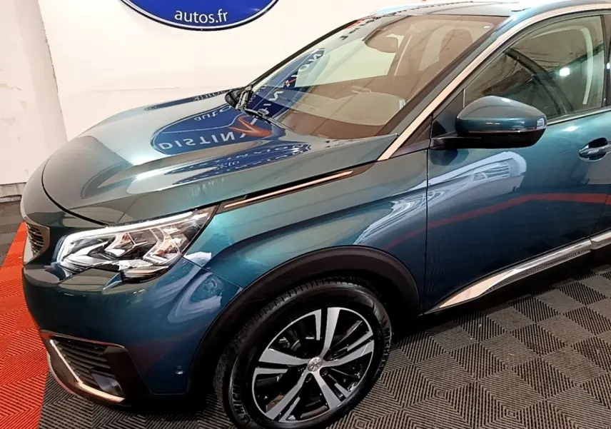 Vue 3/4 avant droit d'un Peugeot 5008 bleu métallisé avec jantes alliage et rétroviseurs noirs brillants.