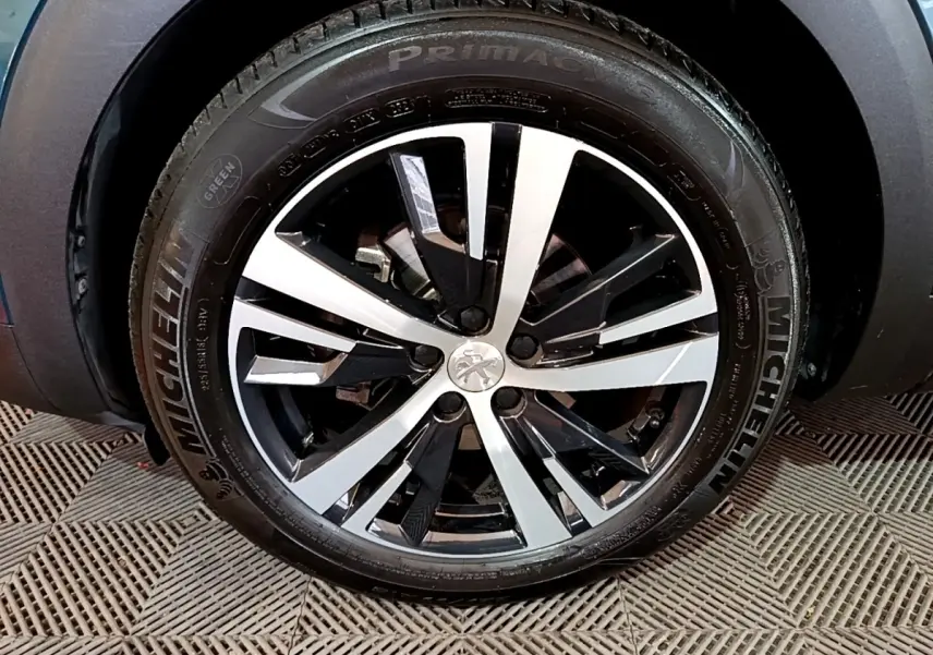 Gros plan sur la jante alliage bicolore du Peugeot 5008 bleu, mettant en valeur le logo lion central.