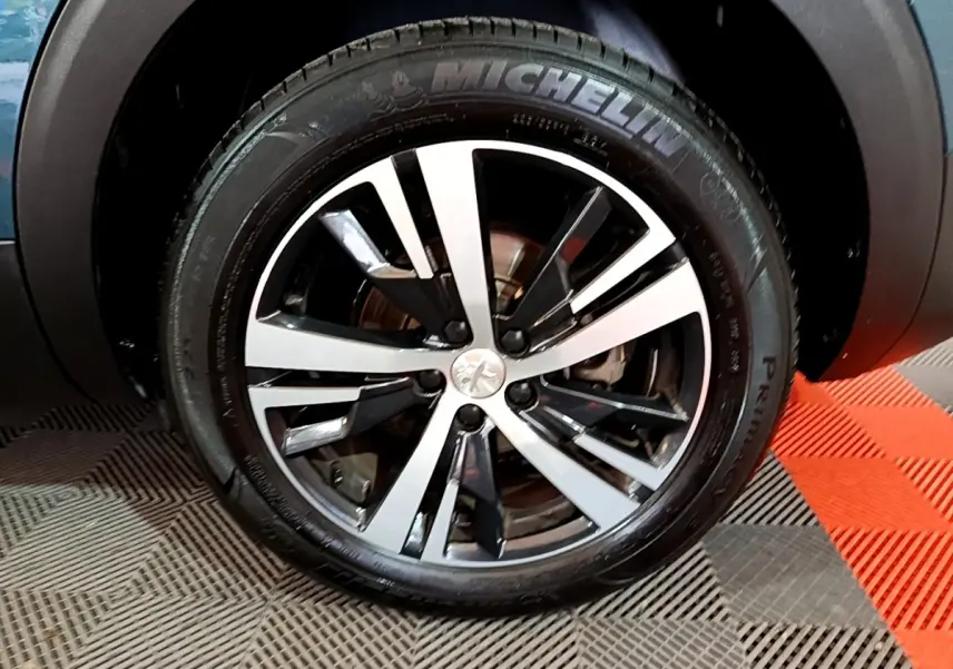Gros plan sur la jante alliage bicolore et pneu Michelin du côté avant gauche d'un Peugeot 5008 bleu 2018.