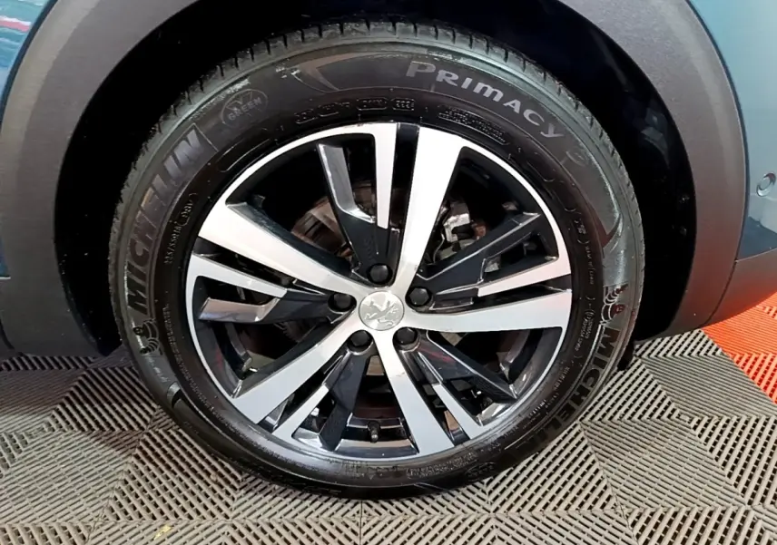 Gros plan sur la roue avant droite du Peugeot 5008 bleu, jante alliage bicolore et pneu Michelin Primacy 3.