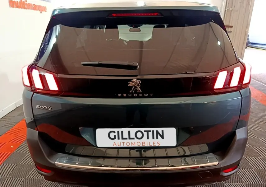Vue arrière d'un Peugeot 5008 bleu avec feux arrière LED caractéristiques et logo lion central visible.