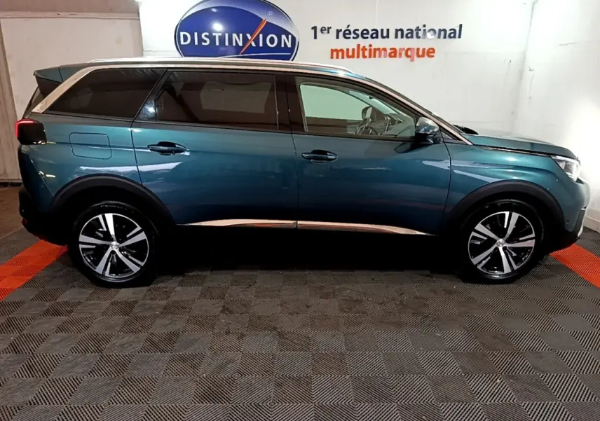 Profil côté droit du Peugeot 5008 bleu 2018 avec jantes alliage et vitres teintées dans un showroom intérieur.