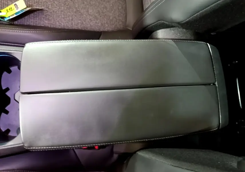 Vue rapprochée de l'accoudoir central noir en cuir entre les sièges avant du Peugeot 5008 bleu 2018.