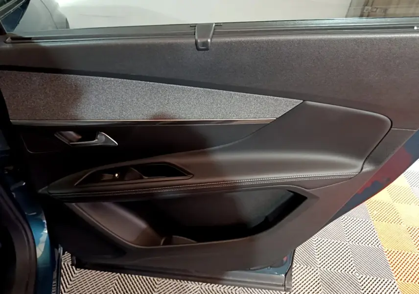Vue rapprochée de la porte côté gauche du Peugeot 5008 bleu, avec garniture noire et poignée argentée.