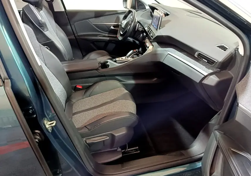 Intérieur côté conducteur du Peugeot 5008 bleu 2018, montrant sièges bi-matière et tableau de bord avec écran tactile.