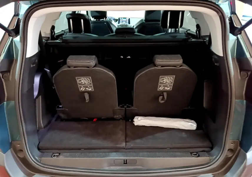 Vue arrière du coffre ouvert d'un Peugeot 5008 bleu, montrant la 3ème rangée de sièges individuels et l'intérieur sombre.