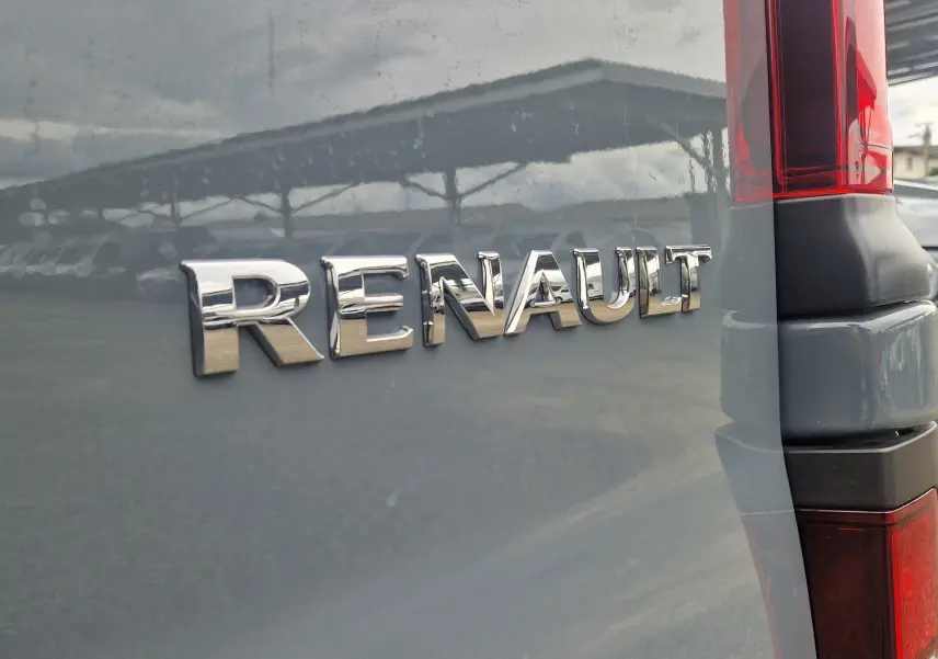 Gros plan sur l'arrière droit gris urbain du Renault Trafic Fourgon avec logo chromé et feu arrière rouge.