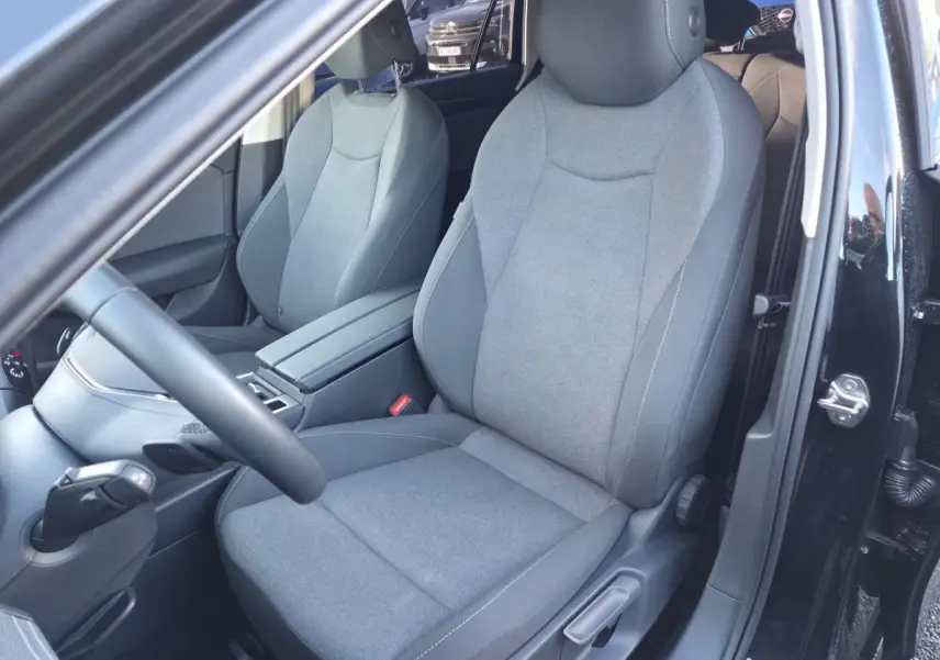 Vue intérieure côté conducteur de la Volkswagen Passat SW noire 2024, sièges tissu gris et volant multifonction cuir.