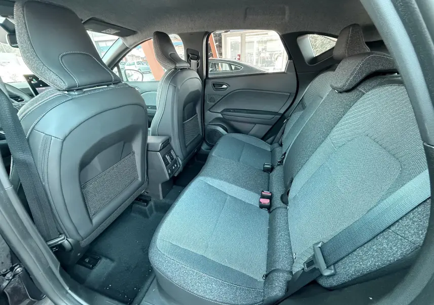 Vue intérieure arrière côté droit du Renault Captur 2025 noir, sièges tissu gris et rangements au dos des sièges avant.
