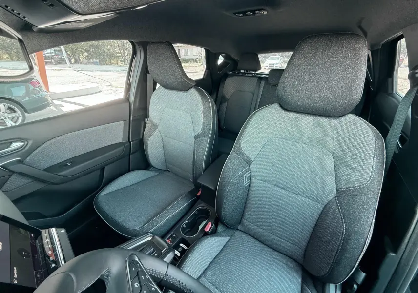 Vue intérieure avant du Renault Captur 2025 noir, montrant les sièges tissu gris et noir avec détails contrastants.