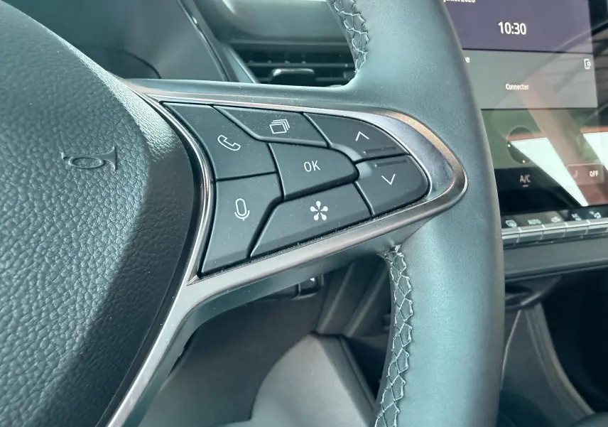 Gros plan sur les commandes au volant noir du Renault Captur 2025, avec écran tactile et tableau de bord en arrière-plan.