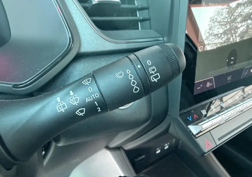 Gros plan sur la commande des essuie-glaces dans l’habitacle noir du Renault Captur 2025, avec tableau de bord et écran tactile.