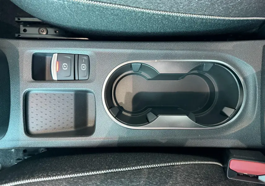 Vue rapprochée de la console centrale avec porte-gobelets et boutons de frein à main sur Renault Captur noir 2025.