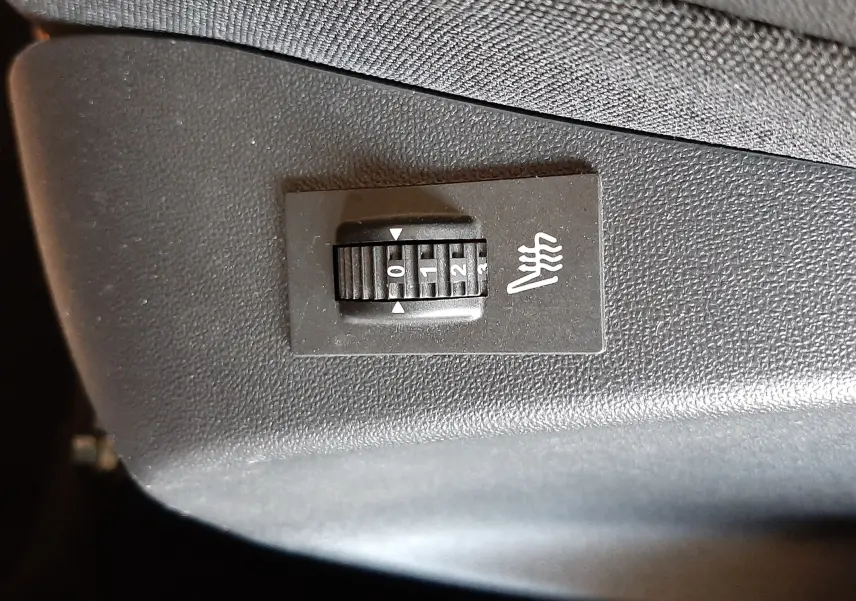 Gros plan sur le réglage de chauffage de siège noir dans l'habitacle d'une Peugeot 2008 GT Line rouge Ultimate Metal 2019.